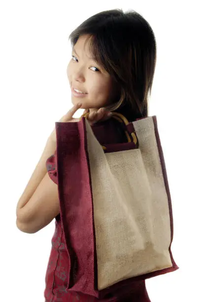 Teenage girl looking  over shoulder while holding shopping-bag