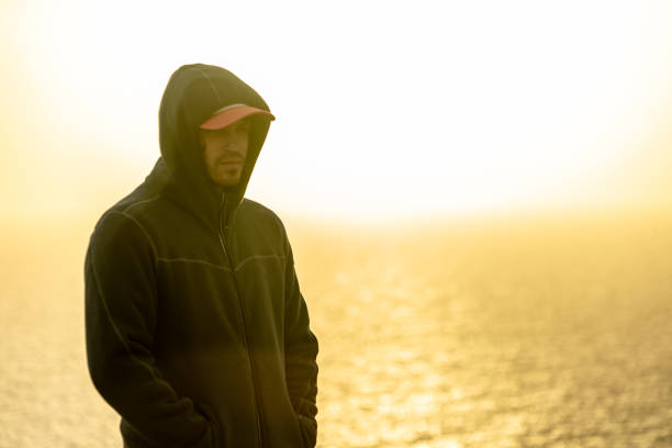 Pensive man looking sideways with sea sunset in the background. Think concept