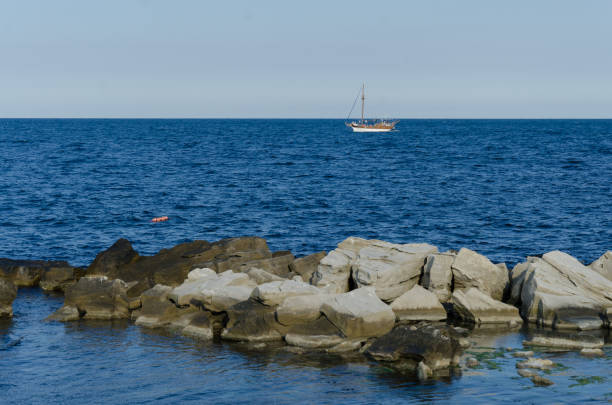 A small white boat sails far out to sea on a clear day