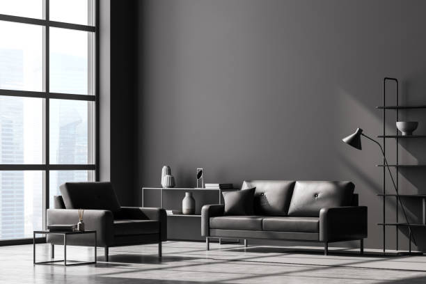 istock Modern living room interior, black wall and huge panoramic window with Singapore city view. Dark grey sofa and armchair, coffee table, bookshelves, lamp and chest of drawers. Concrete floor. 1314514549