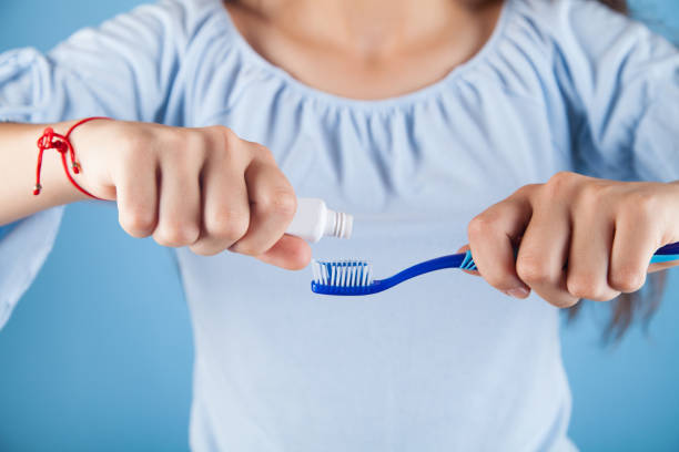istock A girl holding a toothbrush on a blue background. 1314520738