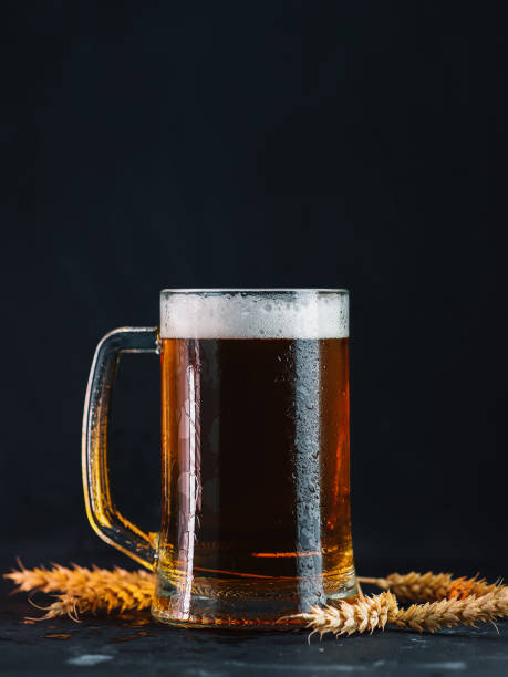 istock Pint mug of light beer on a black background, wheat ears 1314521028