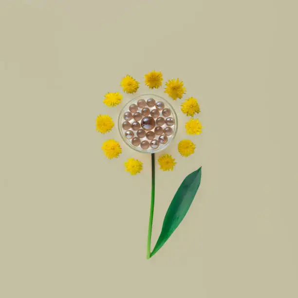 Futuristic flower with glass pearls in the center and with dandelion petals on beige background
