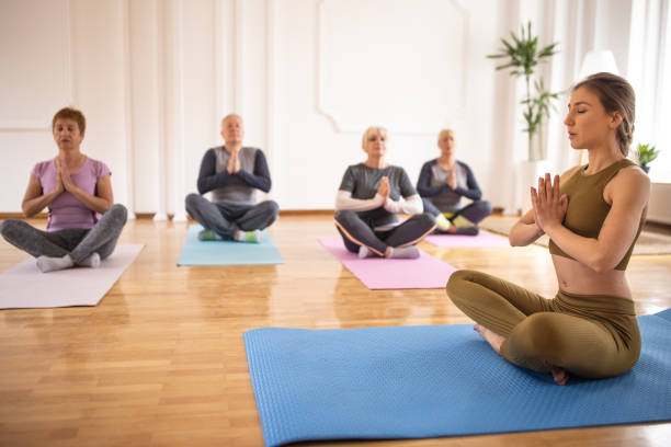 istock Yoga instructor and senior people meditating in prayer pose during yoga class 1314528201