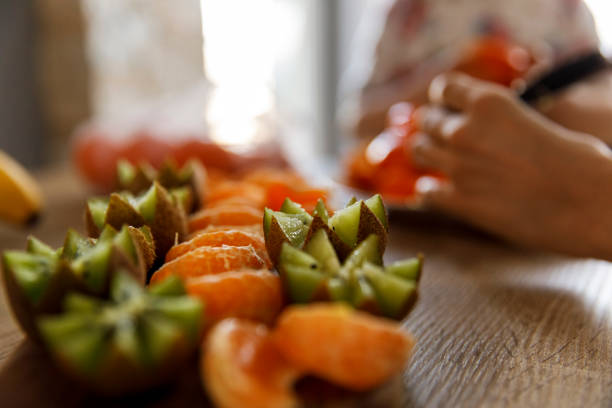 Close up shot of delicious zig zag cut up kiwi fruit and juicy tangerine slices arranged on a platter.