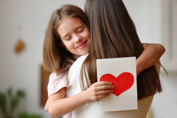 istock Happy daughter with greeting card hugging mother 1314531394