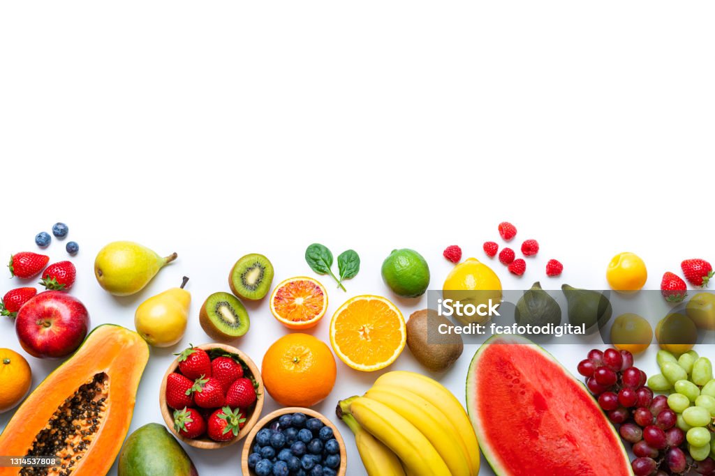 Healthy fresh fruits border on white background Overhead view of multicolored fresh ripe organic fruits shot on white background. The composition is at the bottom of an horizontal frame leaving useful copy space for text and/or logo and includes mango, orange, strawberry, blueberry, kiwi, peach, grape, watermelon, banana, papaya, apple, pear, fig, lime and lemon. High resolution 42Mp studio digital capture taken with SONY A7rII and Zeiss Batis 40mm F2.0 CF lens Fruit Stock Photo