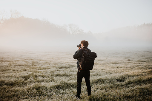 photographer taking pictures on a foggy meadow