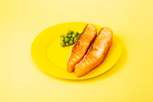 Homemade grilled Salmon dish with peas on yellow plate and yellow background