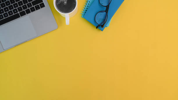 istock Office desk laptop, coffee, notebook and glasses on yellow desk with copy space. 1314544030