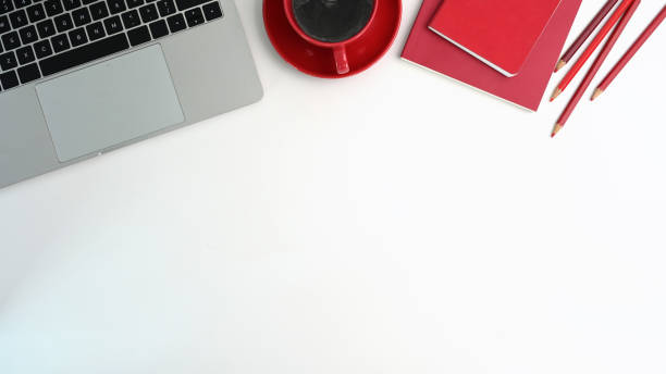 istock Top view office desk with laptop computer, red cup coffee, red notebook and pencil on white table. 1314544062