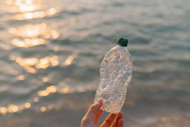 istock Unrecognizable human hand holding a plastic waste bottle recollected into sea water. 1314544143
