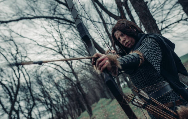 mulher à imagem de arqueiro guerreiro medieval atira um arco na floresta. - archery bow arrow women - fotografias e filmes do acervo