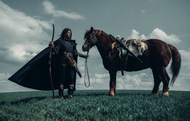 la femme dans l’image du guerrier médiéval reste près du cheval dans le domaine. - bride women standing beauty in nature photos et images de collection