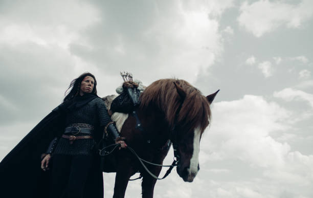 la femme dans l’image du guerrier médiéval reste près du cheval sur le fond de ciel. - bride women standing beauty in nature photos et images de collection
