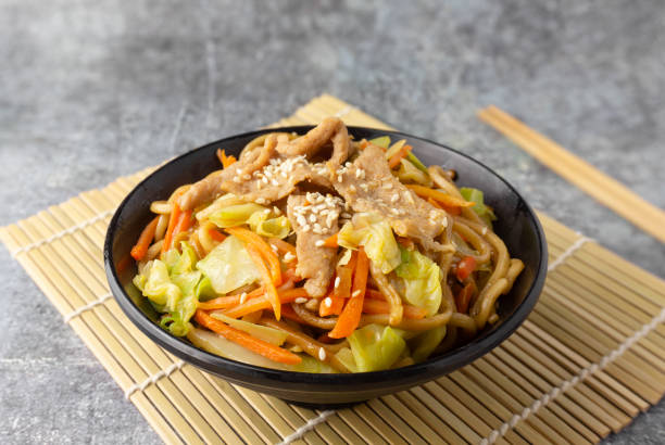 焼きそばの豚肉、黒いボウルに和食。 - chopsticks stir fried vegetable beef ストックフォトと画像