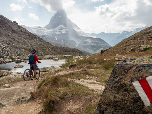 istock Man mountain biker contemplates the Matterhorn mountain 1314547811