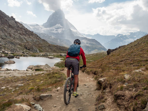 istock Man mountain biker rides along trail below the Matterhorn mountain 1314547963