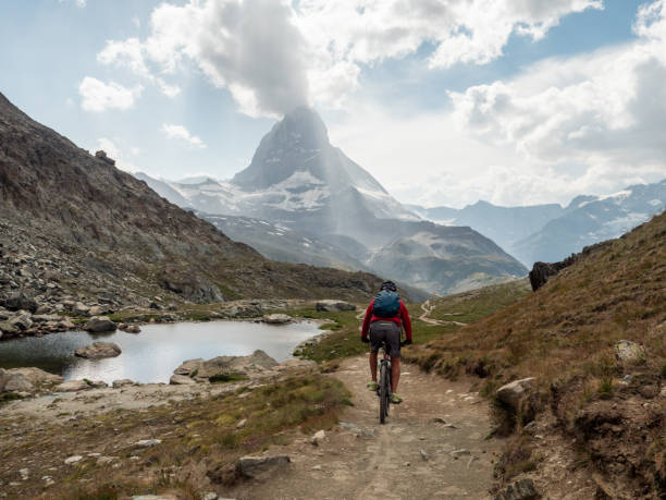 istock Man mountain biker rides along trail below the Matterhorn mountain 1314548040