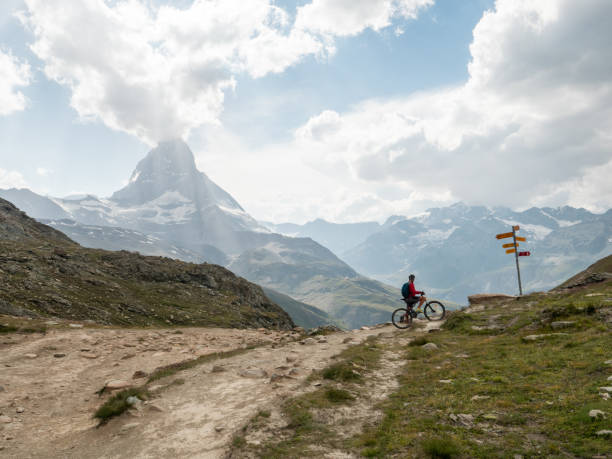 istock Man mountain biker stops at trail signs below the Matterhorn mountain 1314548041
