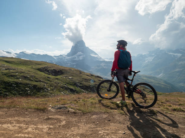 istock Man mountain biker rides along trail below the Matterhorn mountain 1314548353