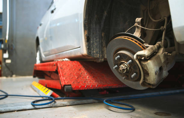 istock closeup car on a lift in a car service with a wheel removed. the technician is checking disk brake and brake caliper with soft-focus and over light in the background 1314549324