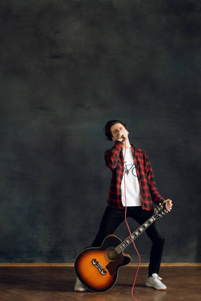 istock A Young man emotionally sings into a microphone and holding a guitar in his hands 1314549589