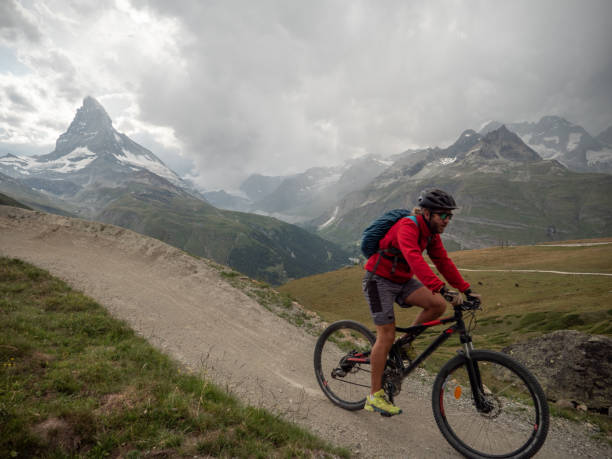 istock Man mountain biker rides along trail below the Matterhorn mountain 1314551461