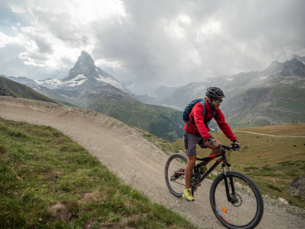 istock Man mountain biker rides along trail below the Matterhorn mountain 1314551479