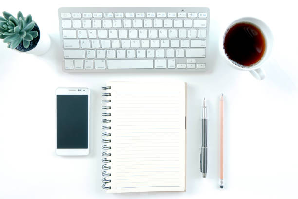 istock Modern white office desk table with laptop computer, smartphone with black screen over a notebook and cup of coffee. Top view with copy space, 1314552768