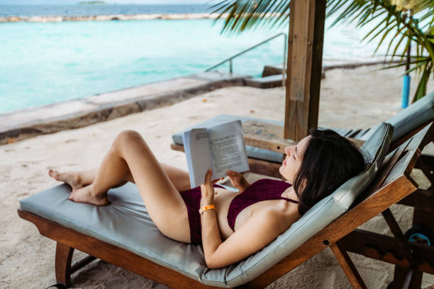 istock Woman reading book by the sea 1314553380