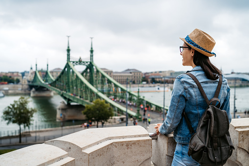 Young Caucasian woman exploring Budapest. Cityscape with Liberty bridge in front.