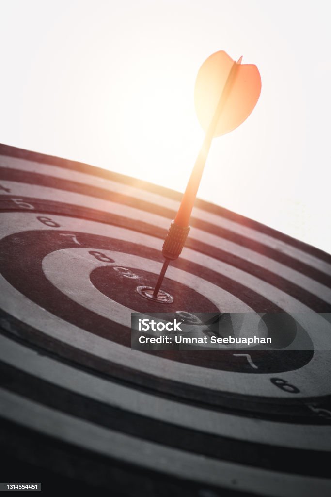 A red dart is placed in the center of a circular target. Communicate the business success of the target, vertical image A red dart is placed in the center of a circular target. Dart Stock Photo