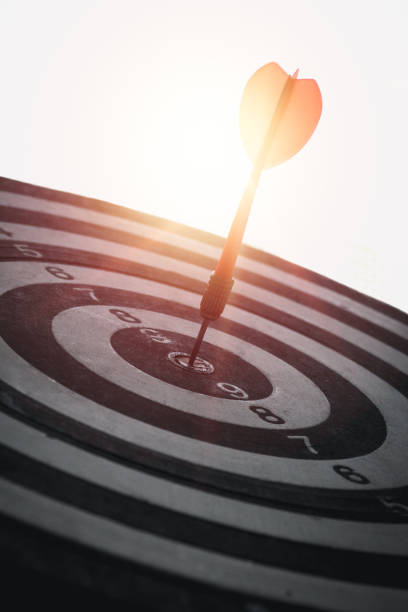 A red dart is placed in the center of a circular target. Communicate the business success of the target, vertical image A red dart is placed in the center of a circular target. bulls eye photos stock pictures, royalty-free photos & images