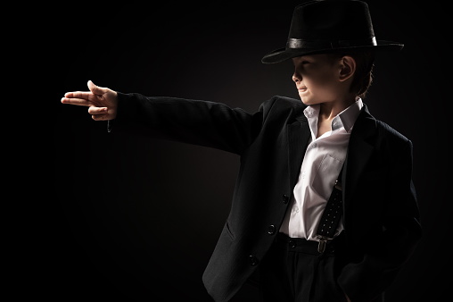 Boy in a gangster with a gun on a black background