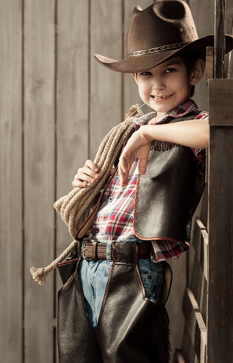 Little boy in an image of a cowboy in a wooden wall with a rope