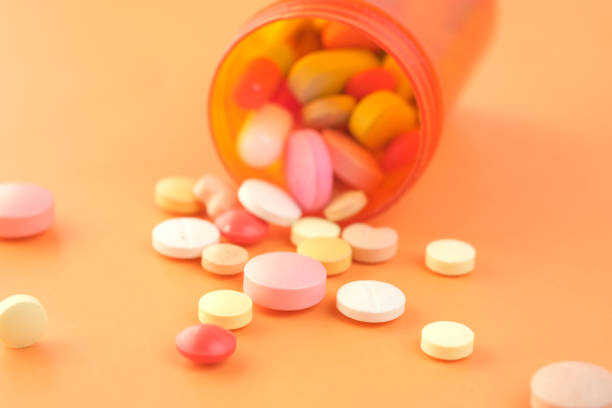 오렌지 배경에 유출 많은 다채로운 알약과 캡슐의 클로즈업 - orange pill close up large group of objects 뉴스 �사진 이미지