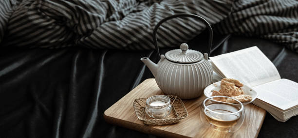 istock Cozy still life with tea, cookies and a book in bed. 1314561696