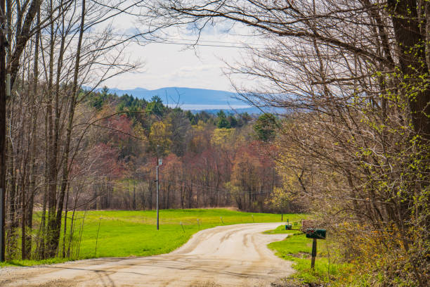 winding dirt winding dirt road in Vermont countryside looking out at Lake Champlain and the Adirondack mountains in New York \n and the Adirondack mountains in New York