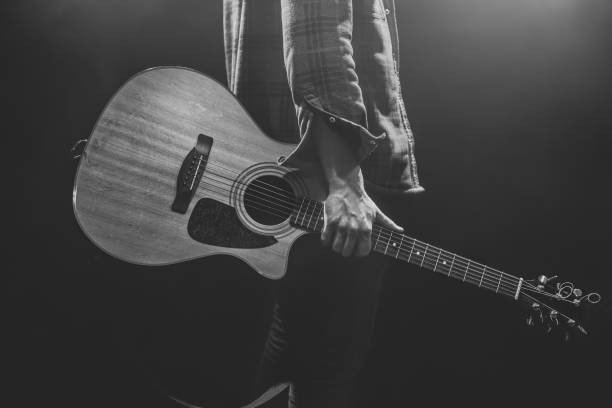 A man holding an acoustic guitar in his hands.