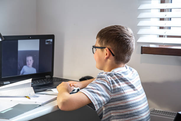 istock Little boy at the table with a laptop and communicates with a friend remotely. 1314572351