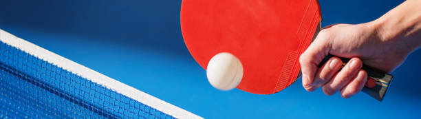main avec une raquette de ping-pong frappant la boule au-dessus de la bannière de table - table tennis table tennis racket racket sport ball photos et images de collection