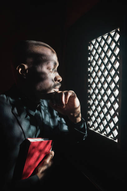 priest with bible in confessional - confession religion imagens e fotografias de stock