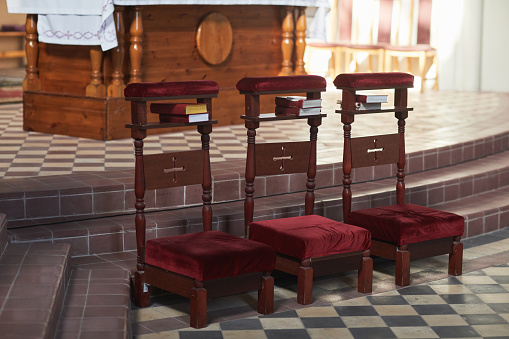 Image of three chairs standing in a row in empty catholic church