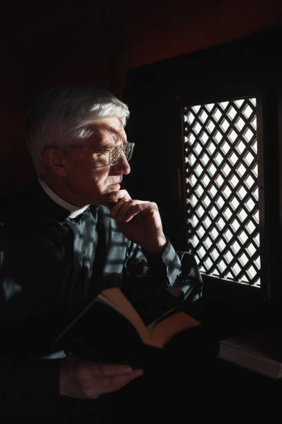 istock Priest with Bible in confessional 1314576034