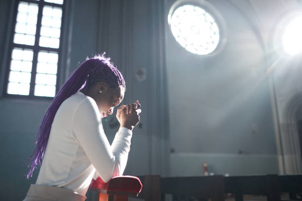 Woman praying in the church African young woman sitting in front of the altar in the church and praying church ladies stock pictures, royalty-free photos & images