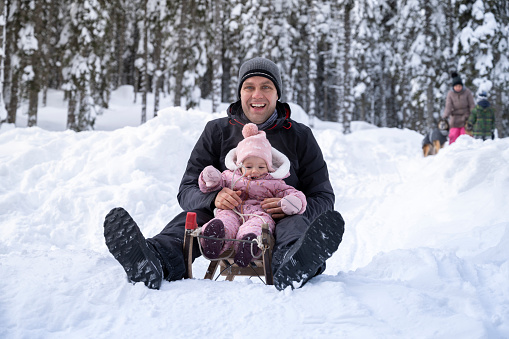 Father and son enjoying tobogganing on snowy landscape.