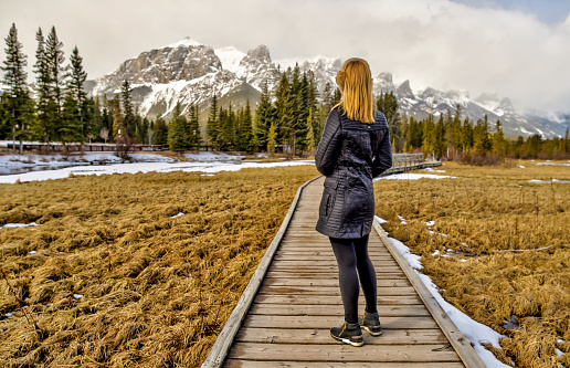 A woman taking in the views of the Rocky Mountains along the Bow River around Canmore Alberta