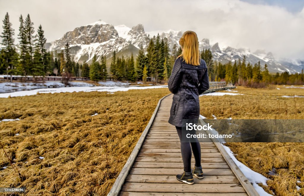 A woman taking in the views of the Rocky Mountains along the Bow River around Canmore Alberta Winter Stock Photo