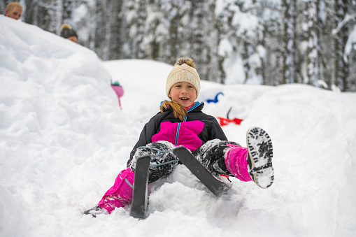 Smiling girl enjoying tobogganing on snowy hill during winter.